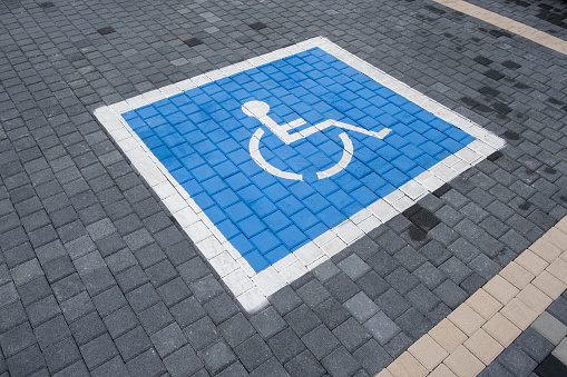 road markings designate a parking space for driver with limited mobility, ensuring accessibility and inclusivity. Painted road tiles as indication of spaces reserved for people with disabilities.