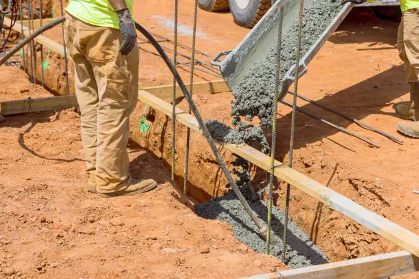 Concrete vibrator being used by construction worker in order to compact concrete into trenches for foundation of house