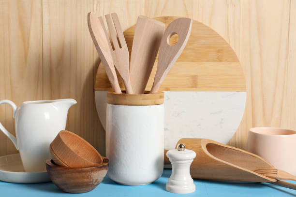 istock Set of different kitchen utensils on light blue table against wooden background 1908307547