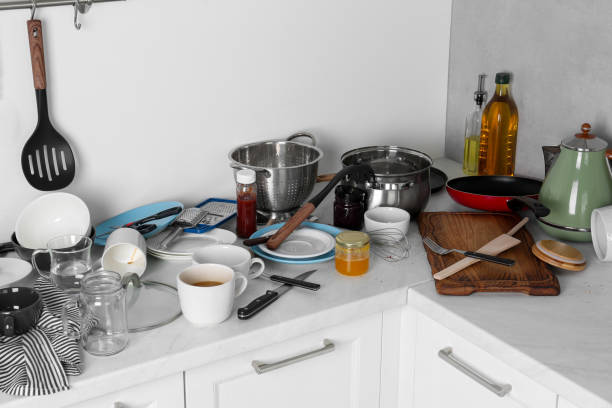 istock Many dirty utensils, cookware and dishware on countertop in messy kitchen 1908307637