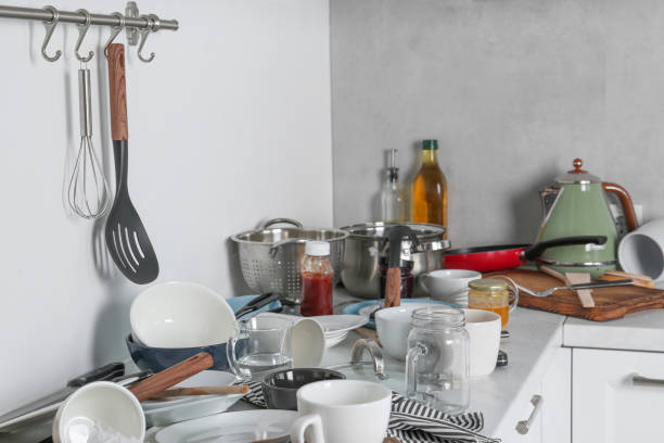 istock Many dirty utensils, cookware and dishware on countertop in messy kitchen 1908307638