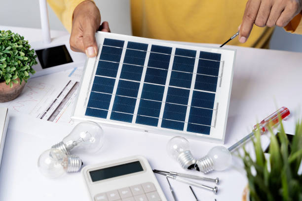 istock Architect is reviewing house blueprint project plan with wind turbine solar cell project. 1908307996