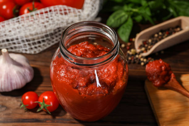 istock Jar of tasty tomato paste and ingredients on wooden table, closeup 1908320507