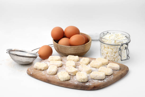 istock Making lazy dumplings. Wooden board with cut dough and ingredients isolated on white 1908330380