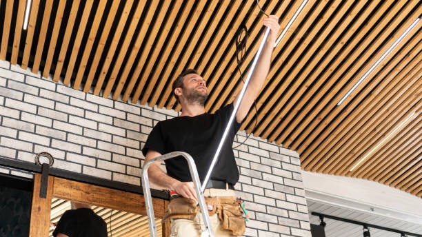 istock A male electrician installs LED strip lamps into a pine plank ceiling. A builder is installing a loft-style ceiling in a modern interior. Service for replacing lamps and repairing electrical wiring. 1908333530