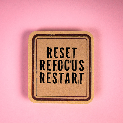RESET REFOCUS RESTART. Cardboard sticker with text on a pink background.
