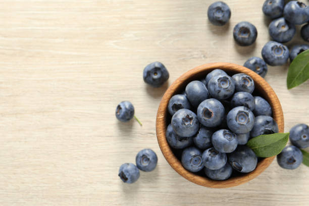 istock Bowl of fresh tasty blueberries on white wooden table, flat lay. Space for text 1908366752