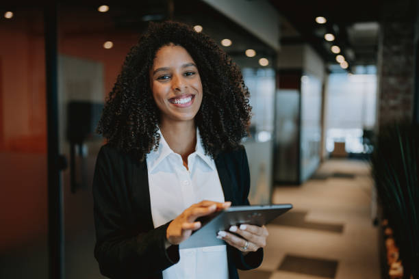 istock Young businesswoman using digital tablet standing in company hallway 1908371822