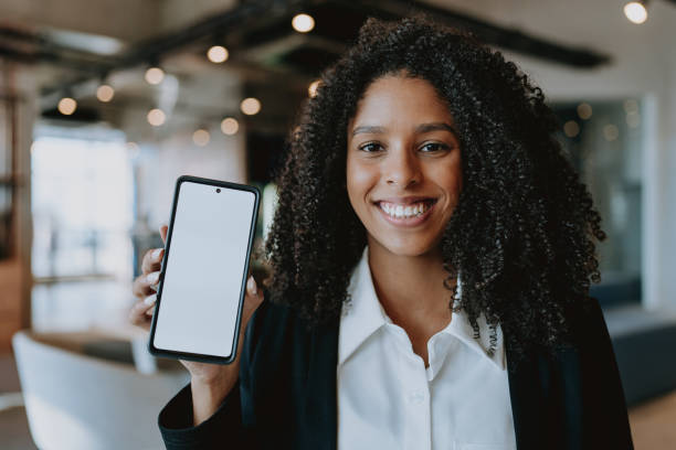 istock Young business woman showing cell phone 1908378343