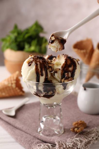 istock Eating tasty ice cream with chocolate topping and nuts at table 1908402576