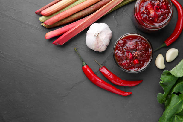 istock Tasty rhubarb sauce and ingredients on black table, flat lay. Space for text 1908407753