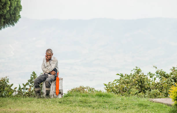 adult man sitting outdoors in his work clothes while concentrating on what is going on around him.