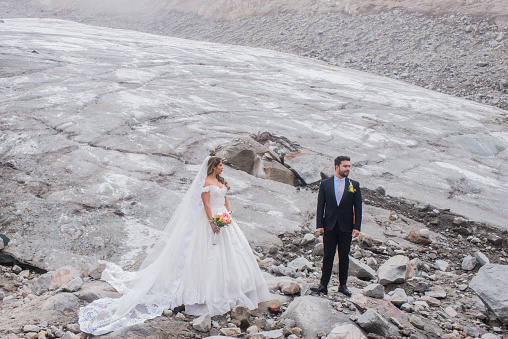portrait of a married couple in the snow while walking on volcanic stone