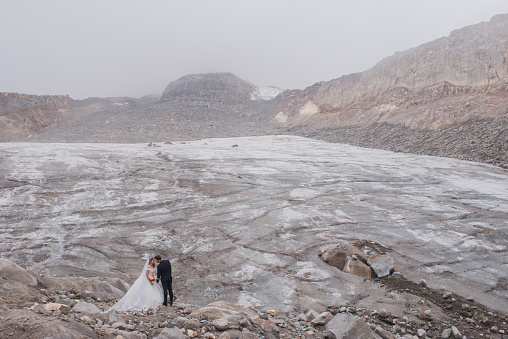 portrait of a newly married couple in the middle of snow-capped mountains and volcanic stone