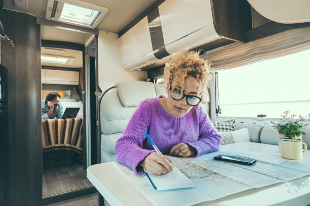 istock woman writes and plans sitting inside the camper while husband relaxes watching a film 1908449171