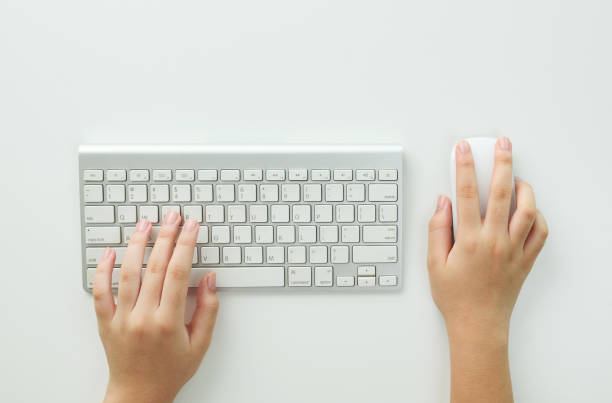 istock Flat lay woman hands on white desk use pc computer silver keyboard and mouse. Top view. Female hands typing on keyboard at white table workplace. Home office workspace with keyboard mouse glasses. 1908450189