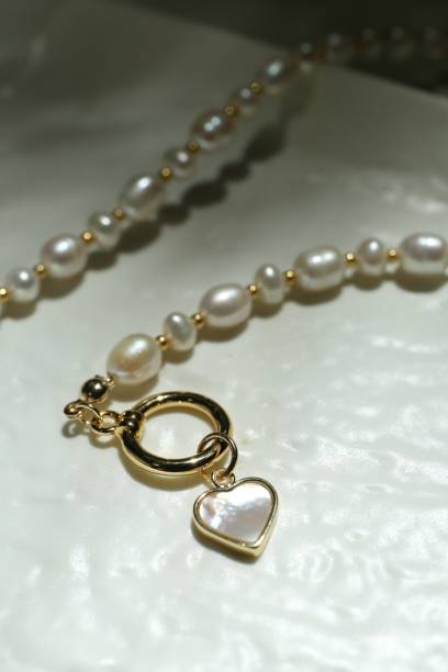 istock Elegant pearl necklace on white textured surface, closeup 1908450725