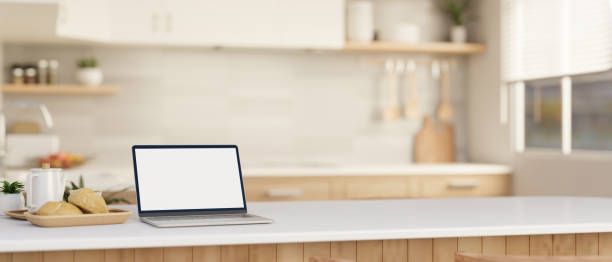 istock A laptop computer mockup on a white kitchen island or countertop in a modern, Scandinavian kitchen. 1908479132