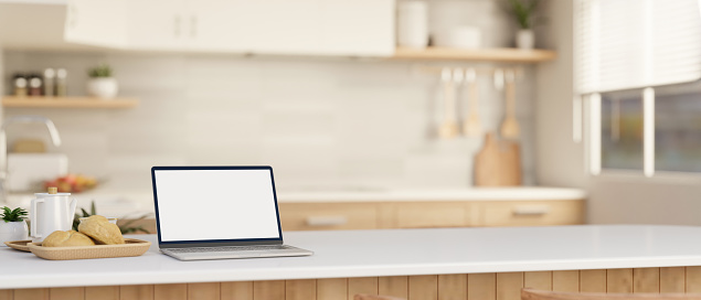 Home workspace, a white-screen laptop computer mockup on a white kitchen island or countertop in a modern, Scandinavian kitchen. blurred background. 3d render, 3d illustration