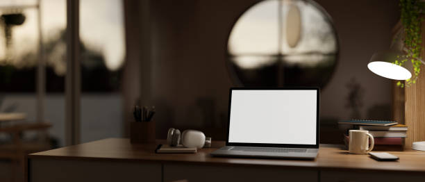 istock A cosy, modern home workspace at night with a white-screen laptop computer mockup on a wooden desk. 1908480159