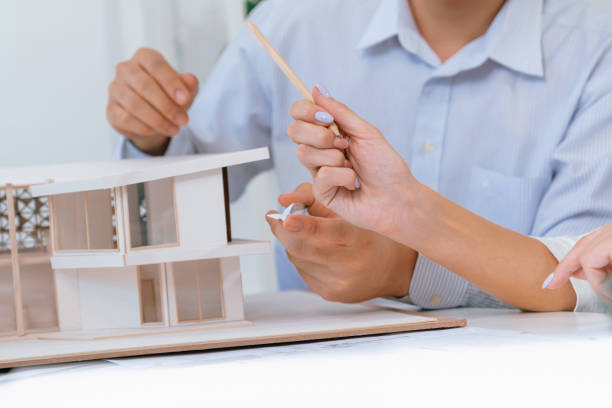 istock Closeup of engineer team working together to measure house model. Immaculate. 1908535798