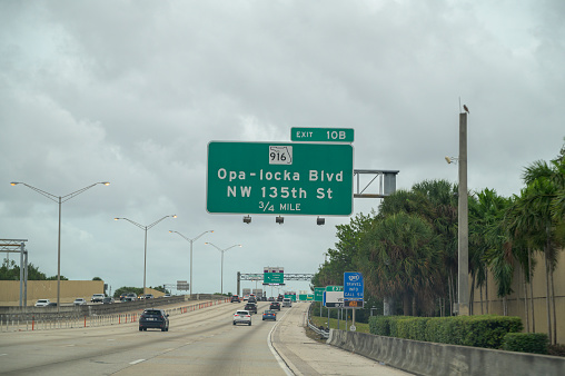 I95 freeway with vehicles - exit for Opa-Locka Blvd and NW 135 street cars.