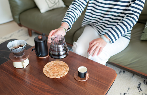 Woman enjoying a coffee ritual at home. She shaking to mix coffee prepared in an alternative way using a dripper and a paper filter