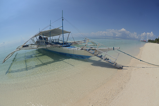 Local traditional Filipino boats or Outrigger boat moored at the Kalanggaman island on a day when the sky is clear and beautiful.