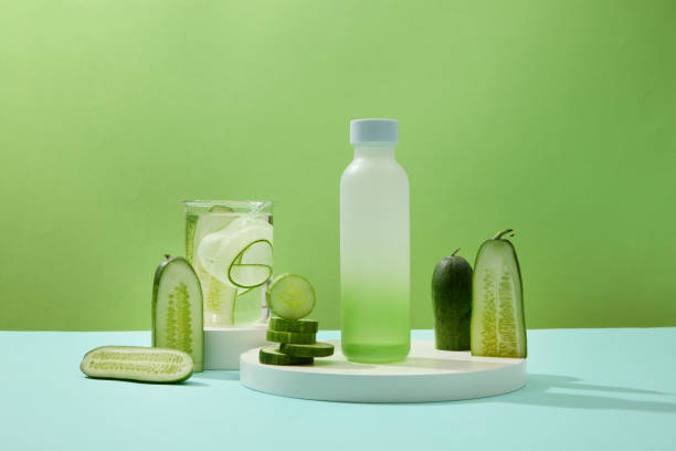 istock A plastic bottle placed on a white podium stands out against a green background with fresh cucumber slices and a glass of detox water. Drinking cucumber water helps purify toxins to brighten skin. 1908571479