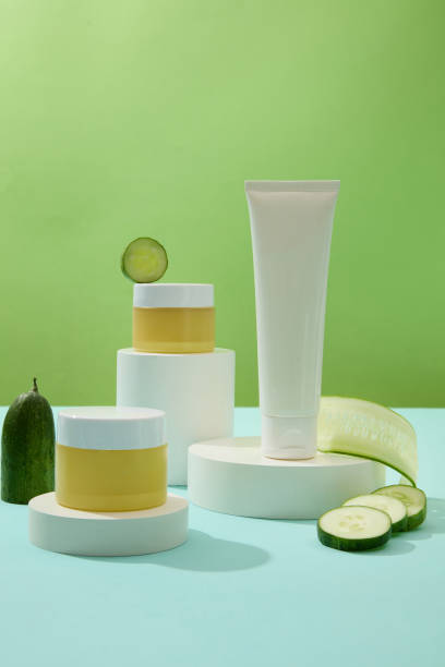 istock A set of unlabeled cosmetics is displayed on white cylindrical platforms with fresh cucumbers on a pastel green background. Cosmetic mockup for ads. 1908572538