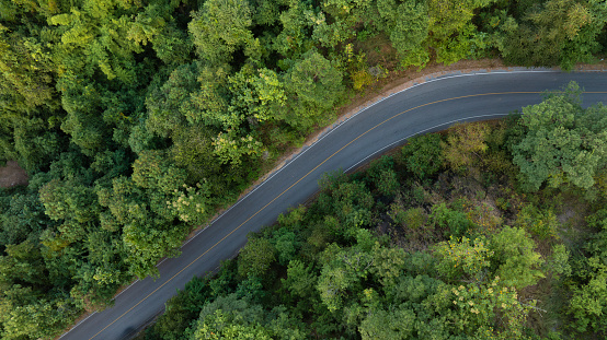 Aerial view of road and dark green forest Natural landscape and elevated traffic roads Adventure travel and transportation ideas for the environment