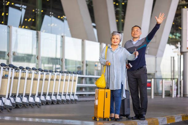 istock Asian senior couple hailing a cab at Airport Terminal. 1908669767