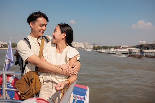 A smiling couple is looking at each other with love during a boat tour.