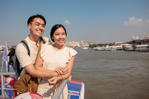 A smiling couple enjoys sightseeing the city from the boat.