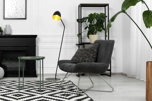 istock Stylish grey armchair, fireplace and small coffee table in living room. Interior design 1908686014