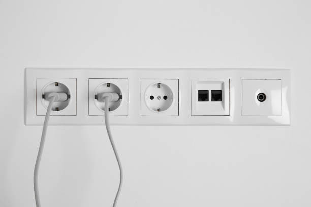 istock Many power sockets with plugs, ethernet and TV coax plates on white wall indoors 1908687609