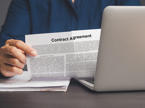 A businessman in a blue shirt tearing up a contract agreement while sitting at a desk in the office. Close-up photo. Terminated agreement concept