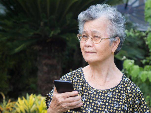 istock Senior woman using mobile phone while standing in a garden 1908691892