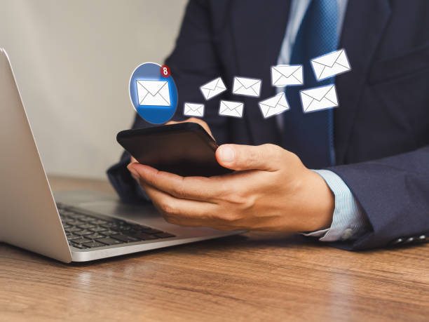 istock Businessman using a smartphone receives a new message with email icons while sitting at the table 1908692449