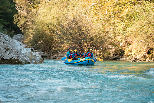 A young Caucasian family, with a mother guiding her three kids on a rafting expedition, emphasizing active family life and adventure in nature.