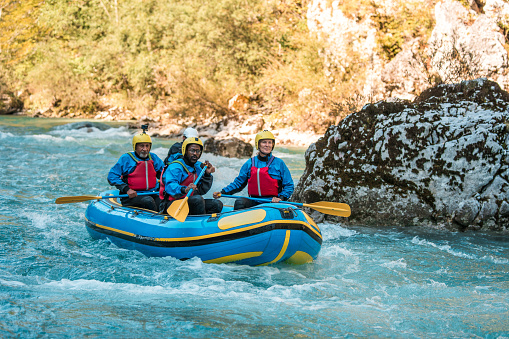 Mature diverse rafters in sync with their guide, tackling the thrilling rapids of a scenic river.