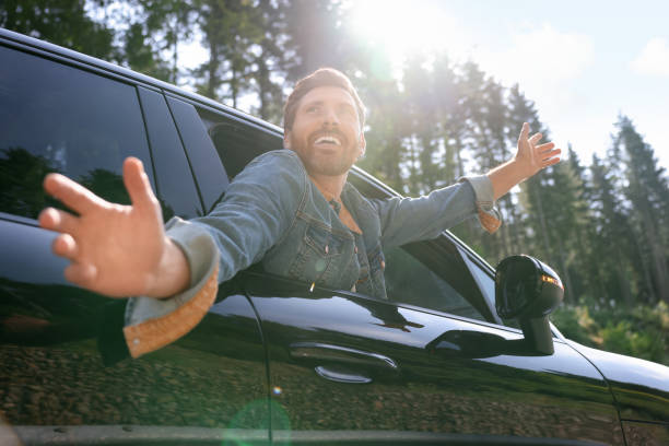 istock Enjoying trip. Happy man leaning out of car window on sunny day, low angle view 1908715465