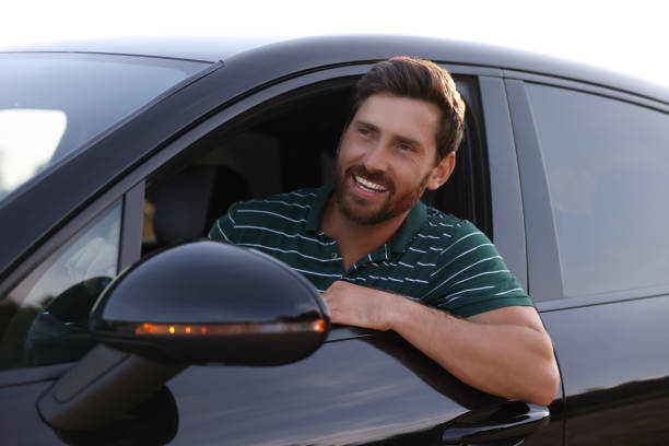 istock Enjoying trip. Happy bearded man driving his car, view from outside 1908715483
