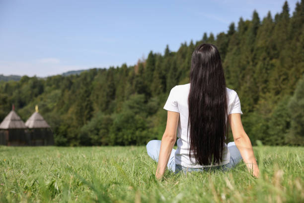 Feeling freedom. Woman enjoying nature on green grass outdoors, back view and space for text