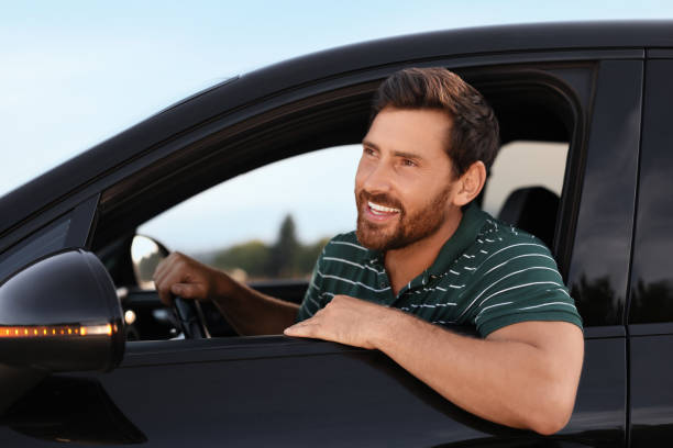 istock Enjoying trip. Happy bearded man driving his car, view from outside 1908718673