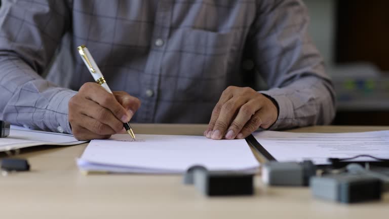 Businessman working on paperwork and stamping approvals, signing documents.