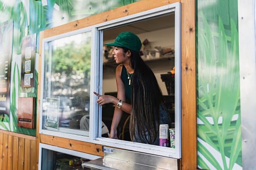 Female barista looks outside food cart window