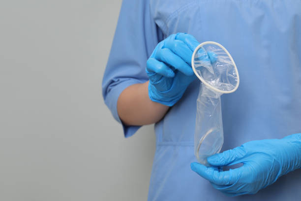 istock Doctor with unrolled female condom on light grey background, closeup. Space for text 1908759400