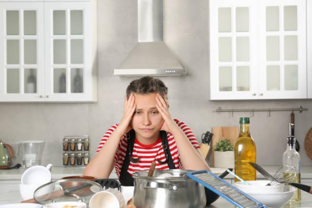 istock Upset woman in messy kitchen. Many dirty dishware and utensils on table 1908760964
