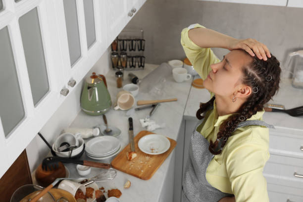 istock Stressed young woman in messy kitchen. Many dirty dishware, utensils and food leftovers on white countertop 1908760967